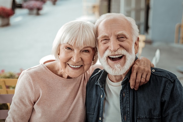 Um casal de idosos abraçados e sorrindo