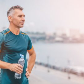 Homem suado segura garrafa de agua e olha para o horizonte