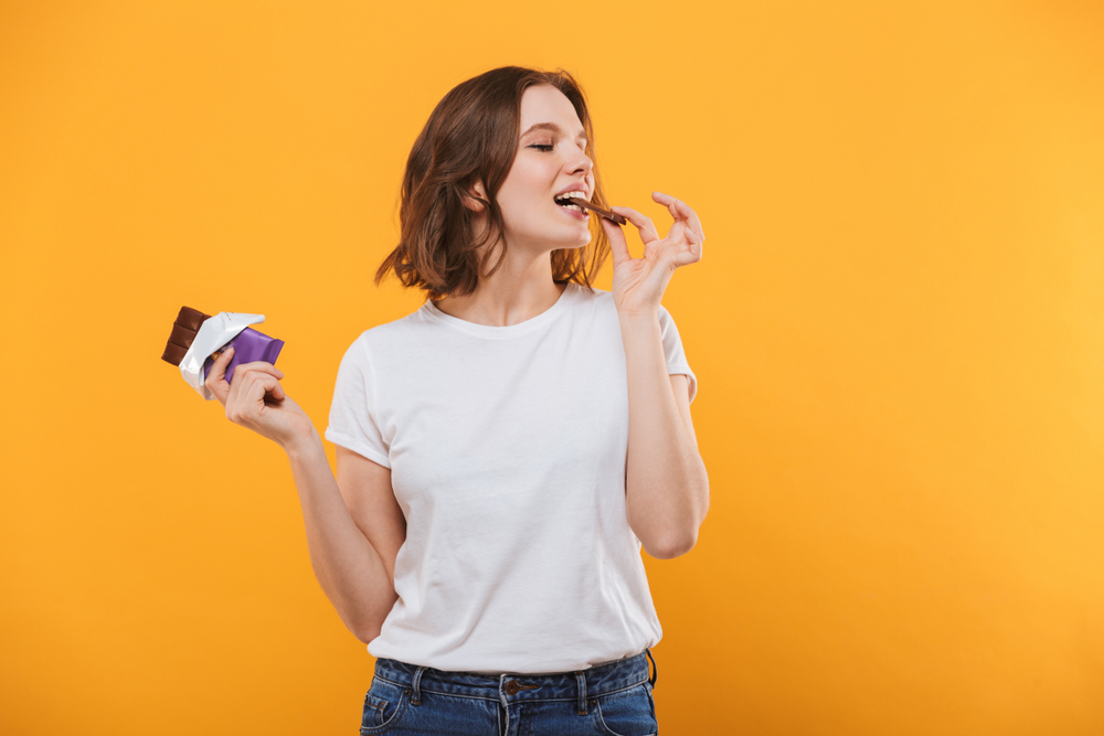 Mulher comendo chocolate para ilustrar os benefícios do alimento para o cérebro