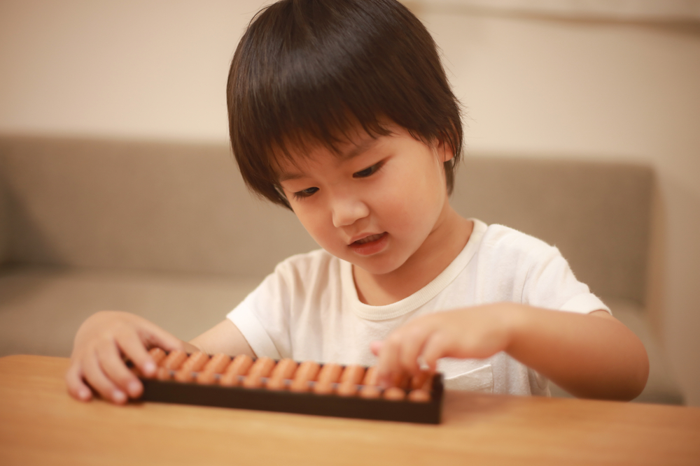 Criança manuseando o ábaco japonês.