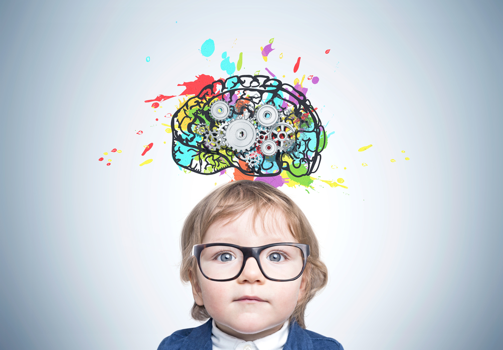 Uma criança usando óculos abaixo de uma ilustração colorida de um cérebro para ilustrar a importância da estimulação cognitiva.