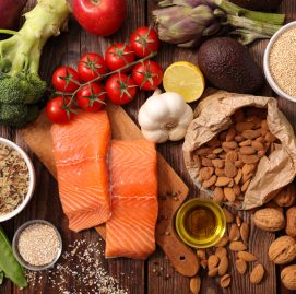 Uma mesa repleta de alimentos como peixes, grãos, verduras, legumes e oleaginosas.