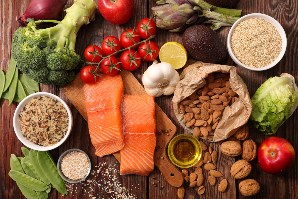 Uma mesa repleta de alimentos como peixes, grãos, verduras, legumes e oleaginosas.