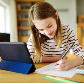 menina escreve no caderno e sorri